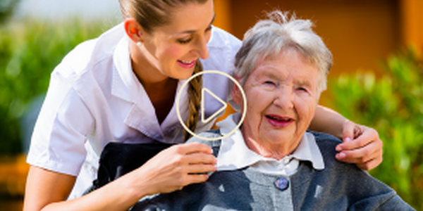 young woman smiling with an older woman in wheel chair